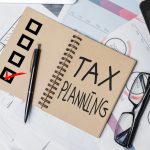 Top view of office desktop with paperwork, glasses and other items. Tax planning concept